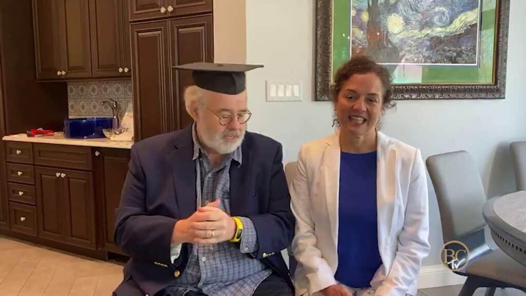 terry crouppen with a graduation cap on talking to a woman