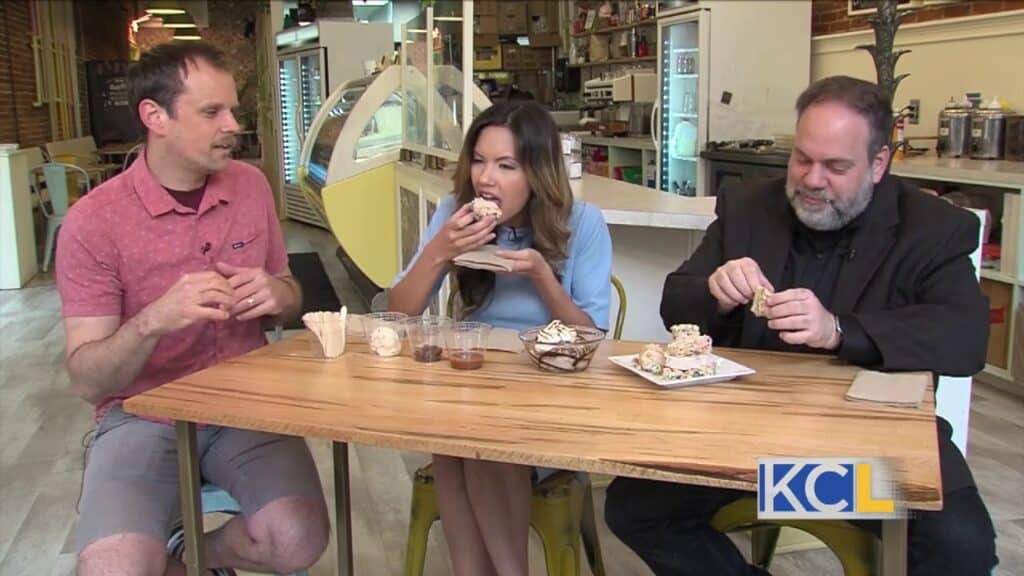 Two men and a woman eating cakes
