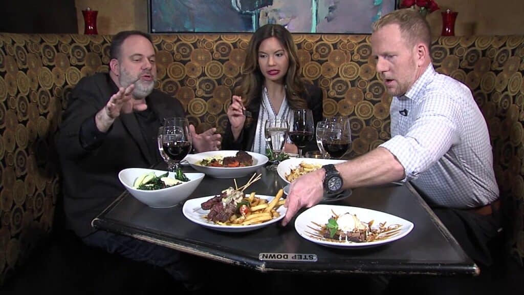 Two men eating at a restaurant with a woman