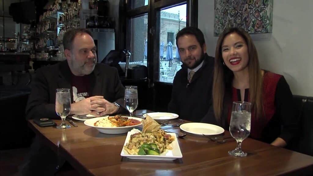 Two men and a woman eating at a restaurant