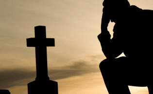 man kneeling at tombstone