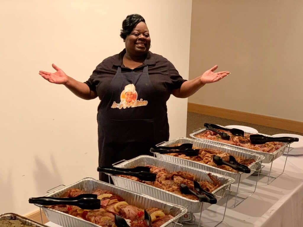 A woman with arms wide spread in front of several delicacies