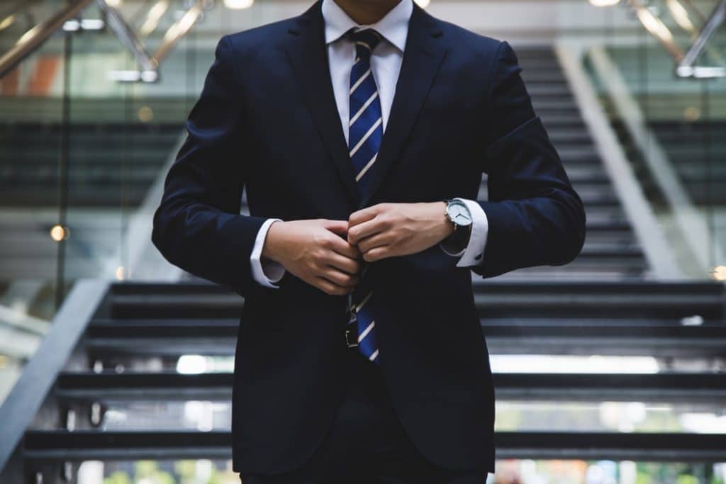 white man in suit buttoning his jacket