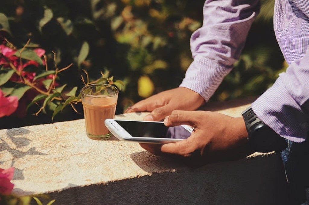 white man on phone with coffee next to him