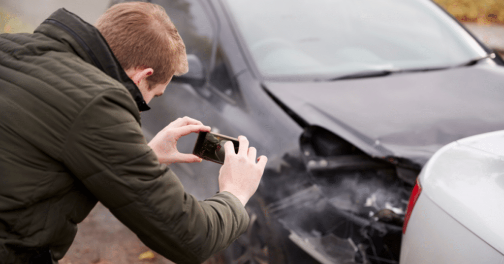 man takes picture of car accident damage