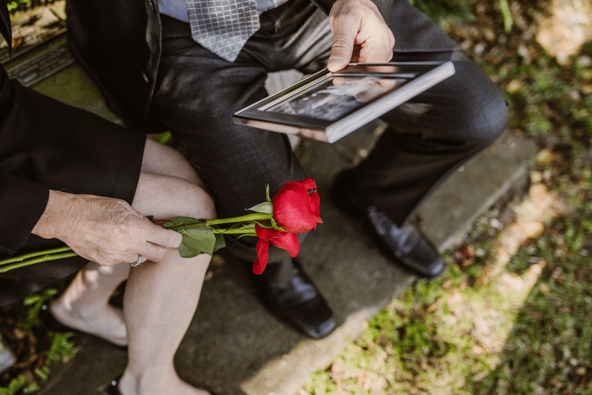 man and woman mourning a death holding a rose and a photo