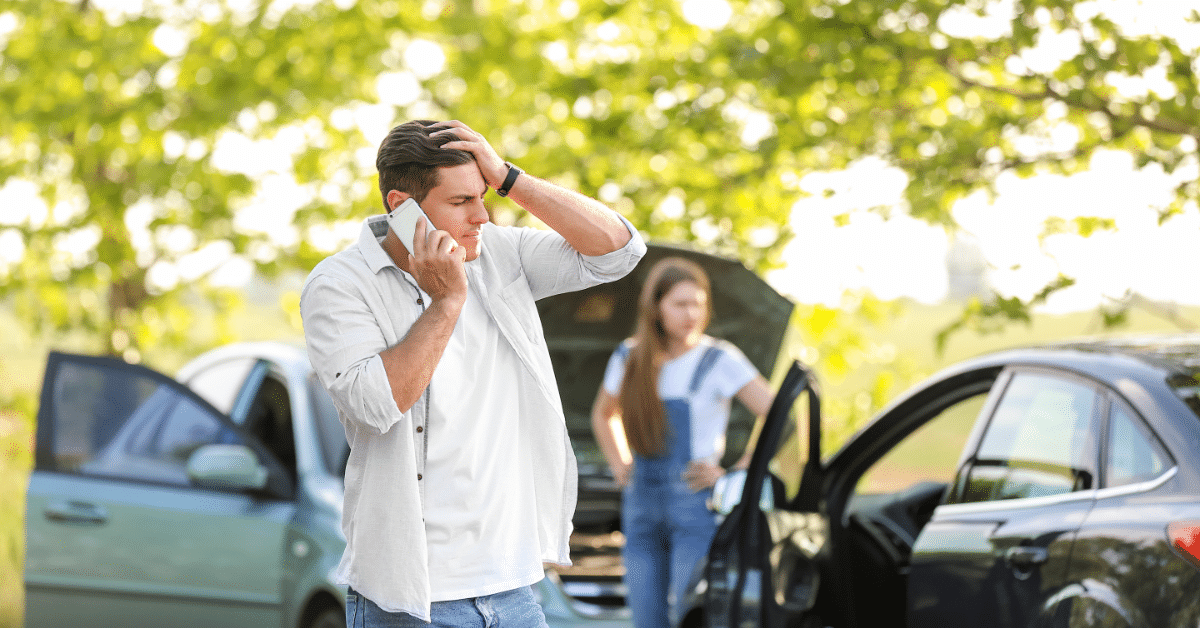 man on phone holding head after car accident