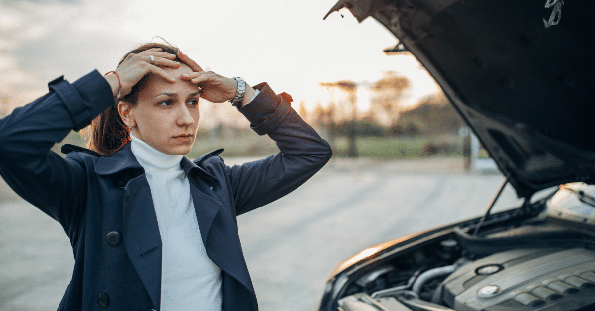 white woman concerned standing next to her car with the hood up