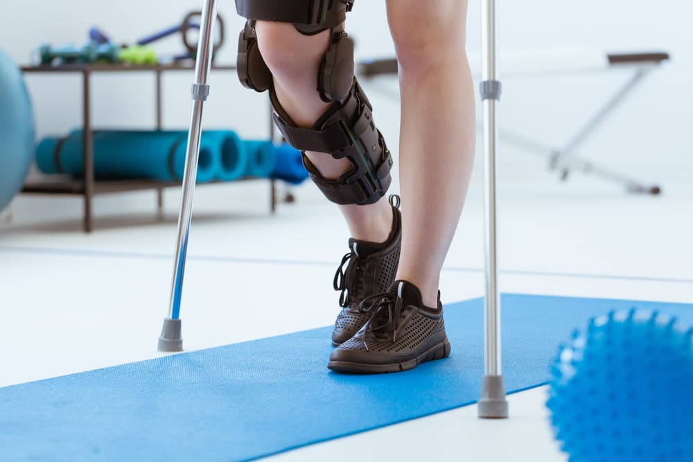 Person in a knee brace using crutches during physical therapy rehabilitation