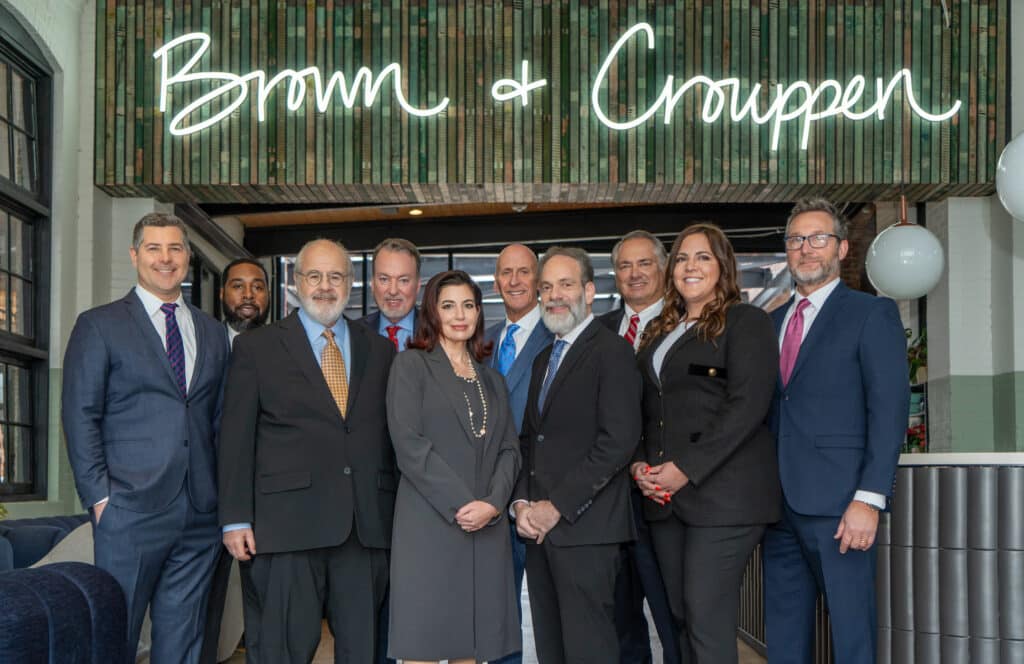 brown and crouppen law firm attorneys standing together smiling in their main lobby