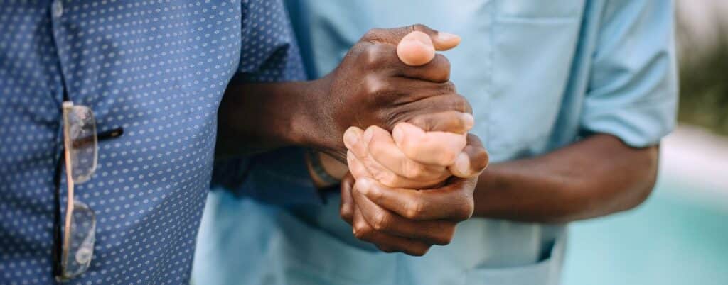 nursing home resident holding the hand of staff member