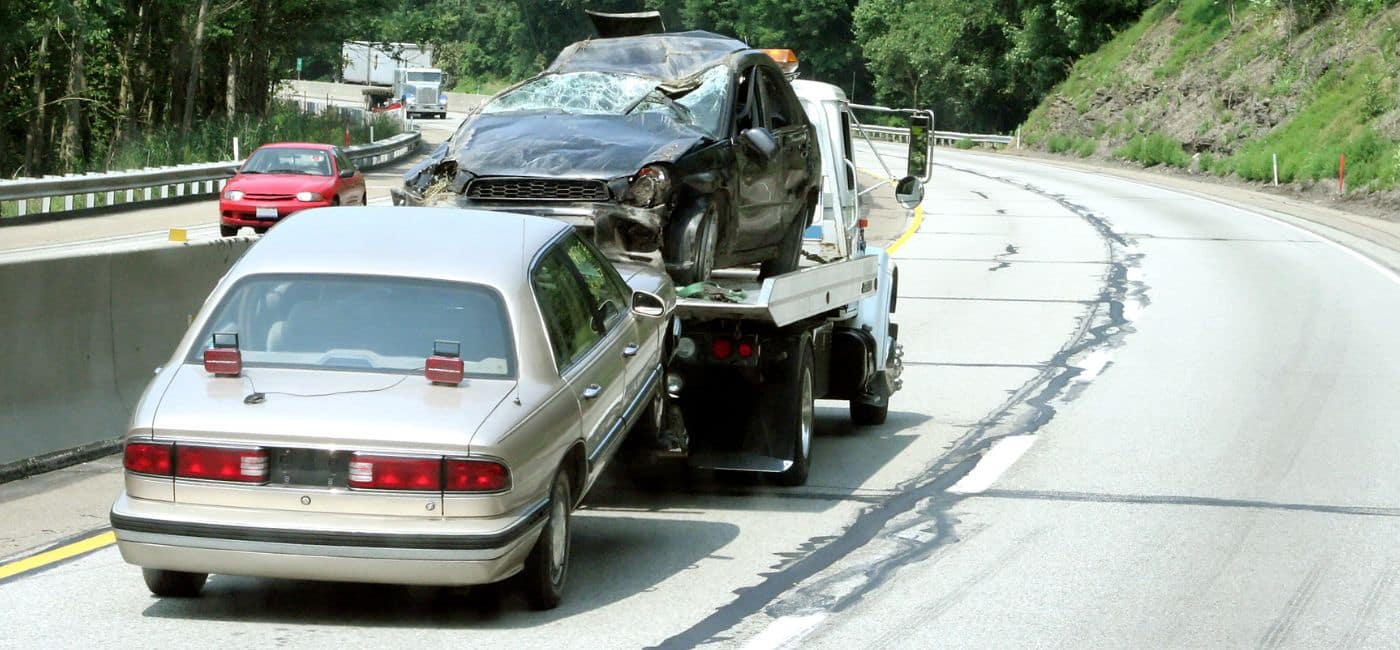 totaled car being towed on highway