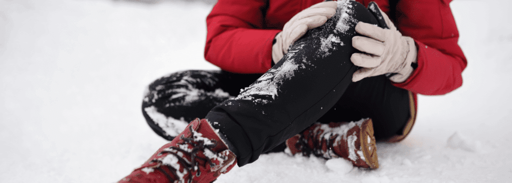 Person holding their knee after slipping on snow