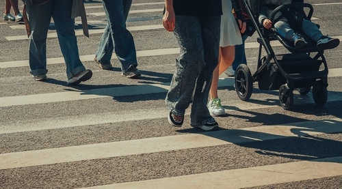 people's legs and a baby carriage on a pedestrian crossing