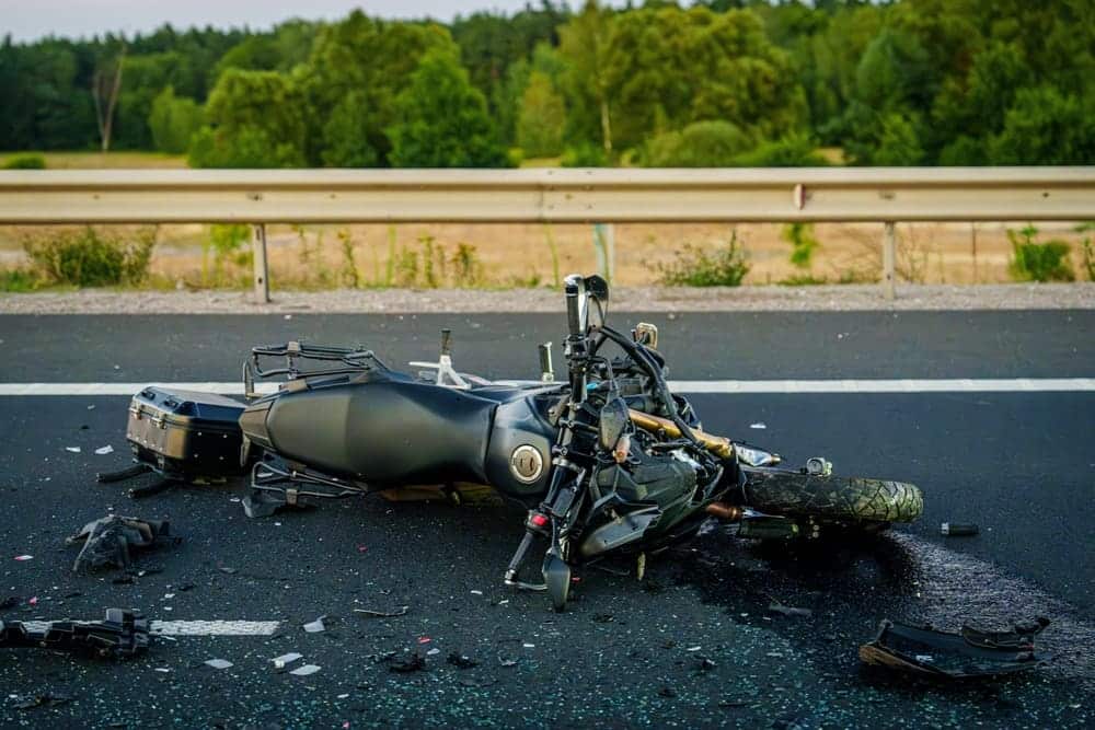 Wrecked motorcycle lying on a highway with scattered debris after a crash